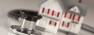 Stethoscope and Model House on Gradated Background with Selective Focus.